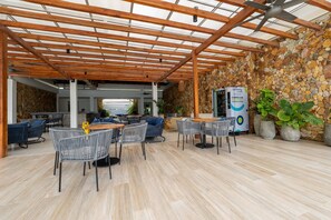 An outdoor patio area with wooden pergola, stone walls, and seating arrangements. - Apartamento premium en Baia Kristal (Cartagena)
