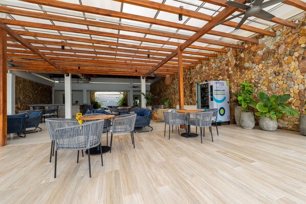 Un área de patio al aire libre con pérgola de madera, muros de piedra y arreglos de asientos.