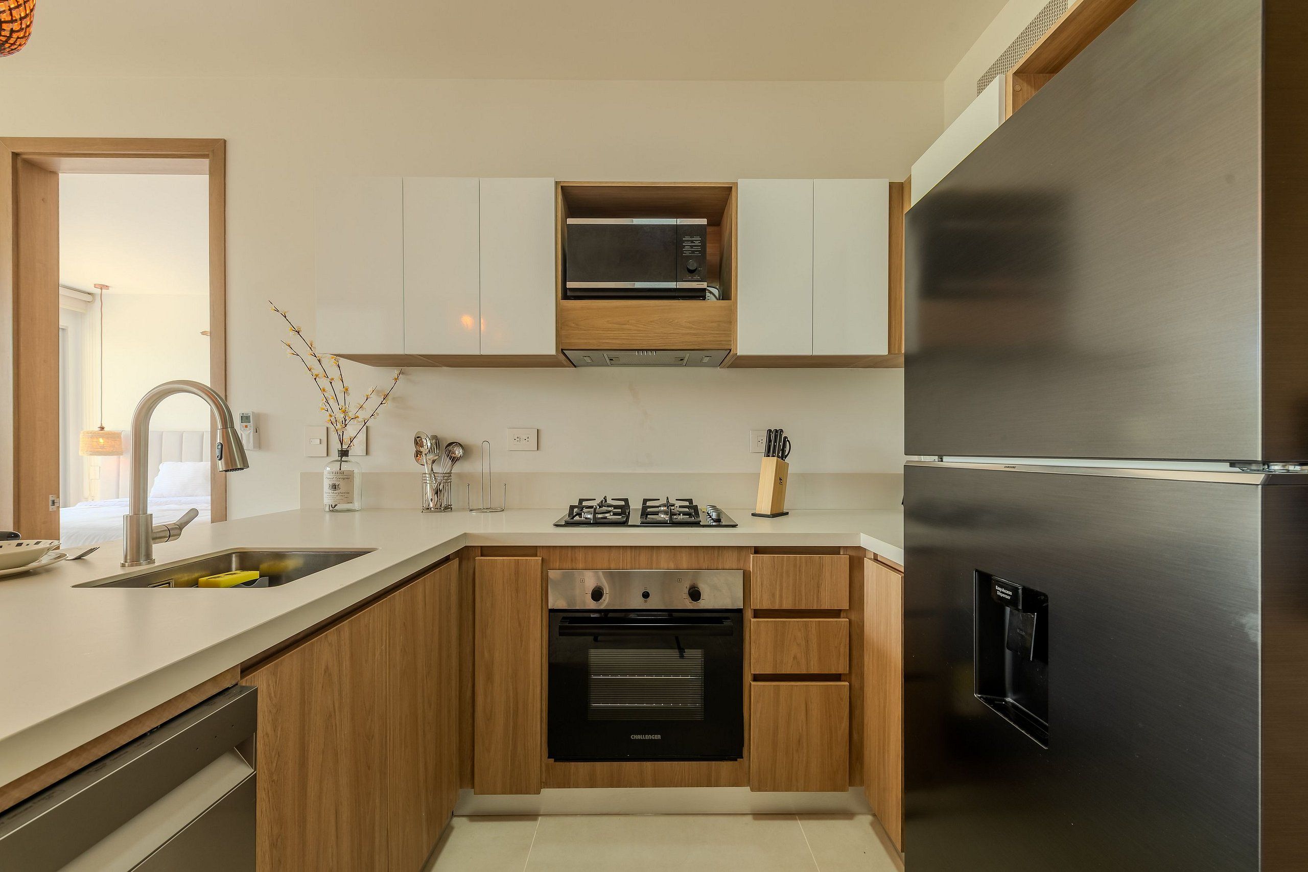 Eine moderne Küche mit Holzausbau, einem Edelstahlkühlschrank, einer integrierten Mikrowelle und einem Geschirrspüler.