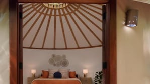 Une pièce aménagée comme une tente, avec un lit, deux tables de chevet et un luminaire fixé au mur.