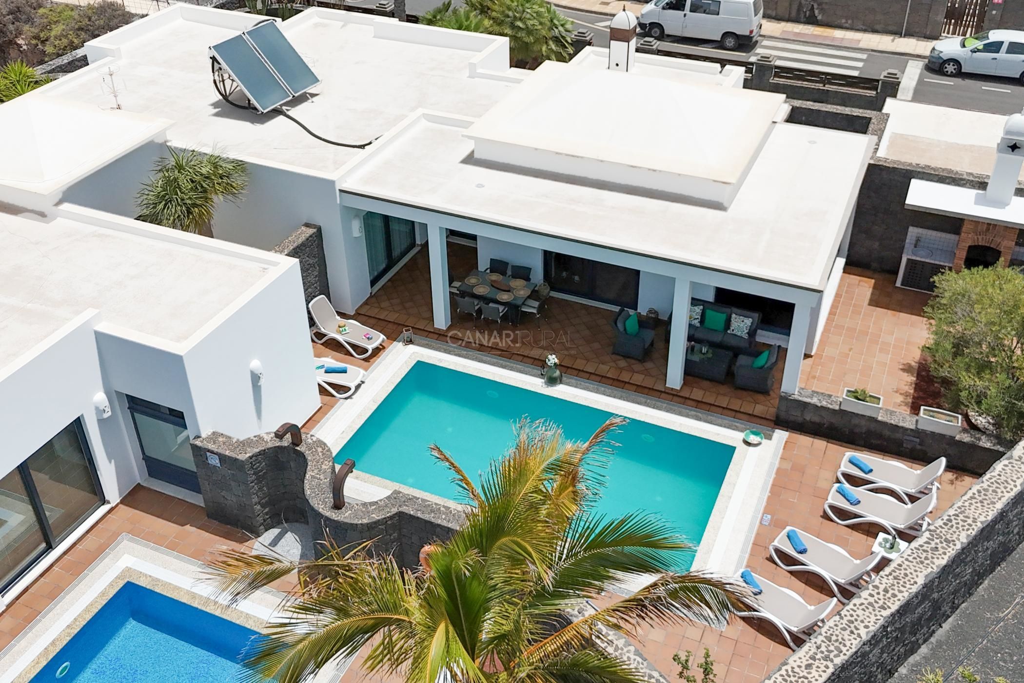 Un edifici modern amb piscina, mobiliari d'exterior i zona de pati coberta.
