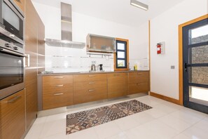 A modern kitchen with wooden cabinets, stainless steel appliances, and a patterned rug. - Stylish villa with private pool near the sea (Yaiza)