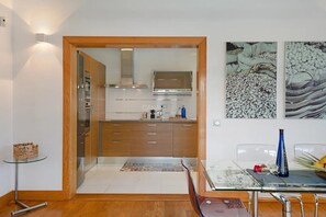 A modern kitchen with wooden cabinets, a stainless steel range, and a glass dining table.