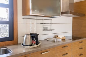 A modern kitchen with a stainless steel kettle, a coffee maker, and a toaster on the counter.