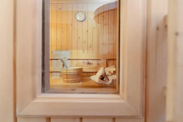 Una sala de sauna con paredes, banco y cubo de madera, además de una toalla.