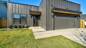 A modern two-story building with a garage, a large window, and a well-maintained lawn.