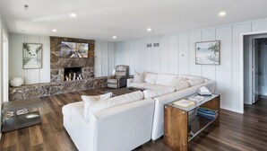 A modern living room with a stone fireplace, white sofas, and a wooden coffee table. - 2 Lakefront Homes: Wide Decks, Great View (Gravois Mills)