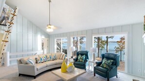 A spacious living room with a curved sofa, two armchairs, and a coffee table. Large windows offer a view of the outdoors. - 2 Lakefront Homes: Wide Decks, Great View (Gravois Mills)