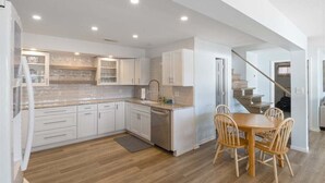 A modern kitchen with white cabinets, a granite countertop, and a dining area with wooden chairs. - 2 Lakefront Homes: Wide Decks, Great View (Gravois Mills)