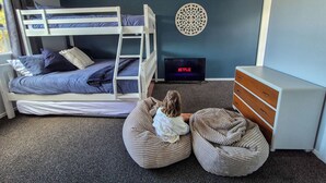 A room with bunk beds, a TV, a dresser, and bean bags. - Comfy family home, stay at our retreat on Brittan St! (Hokitika)