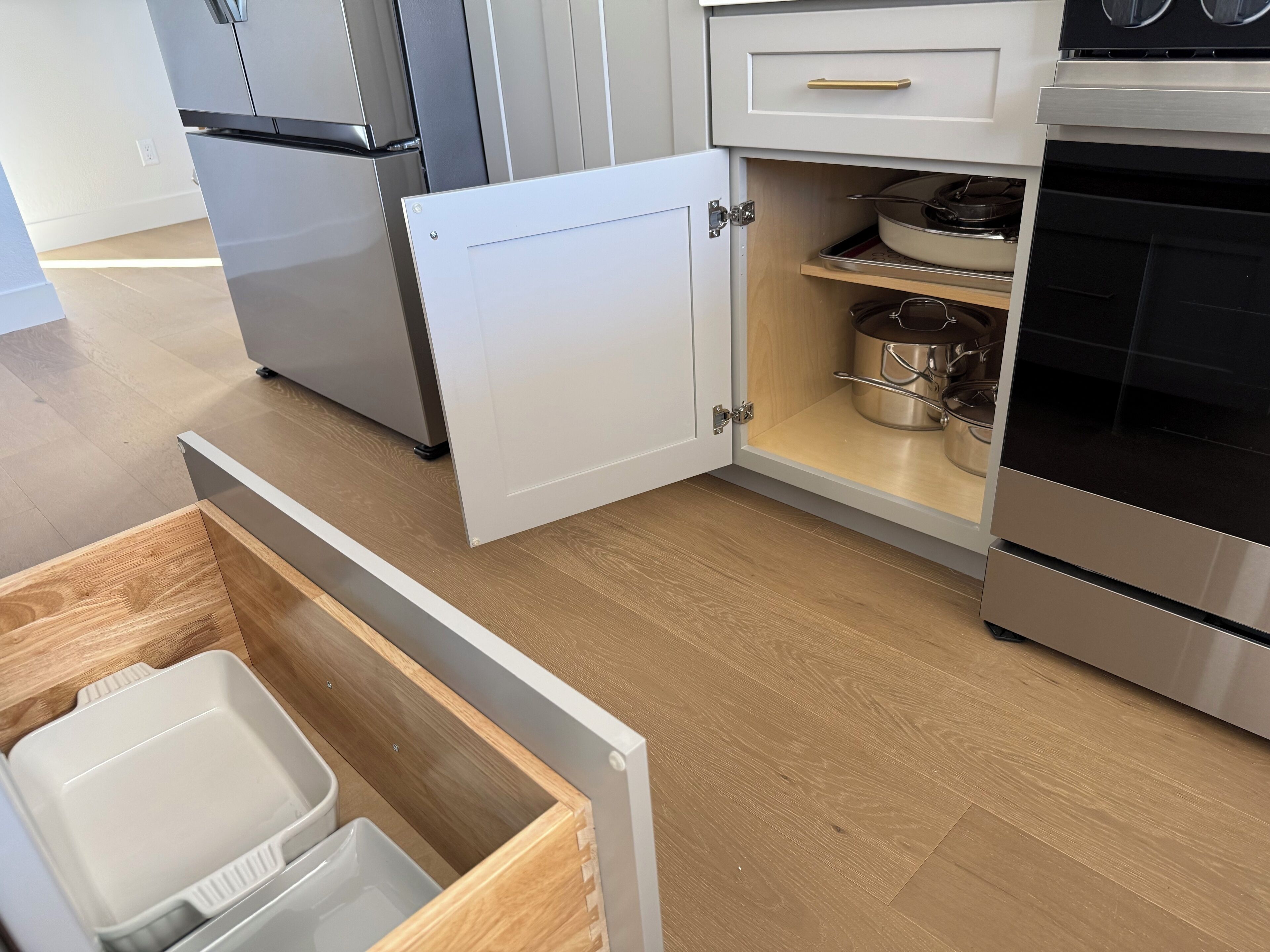 Una cocina con horno empotrado, refrigerador de acero inoxidable y un gabinete blanco con un cajón.