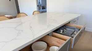 A modern kitchen with a marble countertop, wooden drawers, and white bowls. - Peaceful 3BD/2BA Dog-Friendly Paradise Posada (Scottsdale)