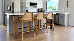A modern kitchen with a central island, wooden chairs, and pendant lighting. - Peaceful 3BD/2BA Dog-Friendly Paradise Posada (Scottsdale)
