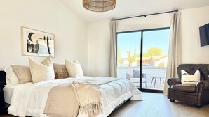 A bedroom with a large bed, a chair, a wicker ceiling light, and a view of the outside. - Peaceful 3BD/2BA Dog-Friendly Paradise Posada (Scottsdale)