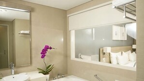 A bathroom with a sink, bathtub, mirror, and a potted orchid. - TreePark Karawang (East Telukjambe)