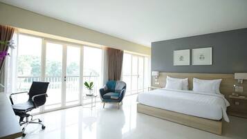 Une chambre d’hôtel avec un grand lit, un bureau, une chaise, une petite table et un balcon avec vue.
