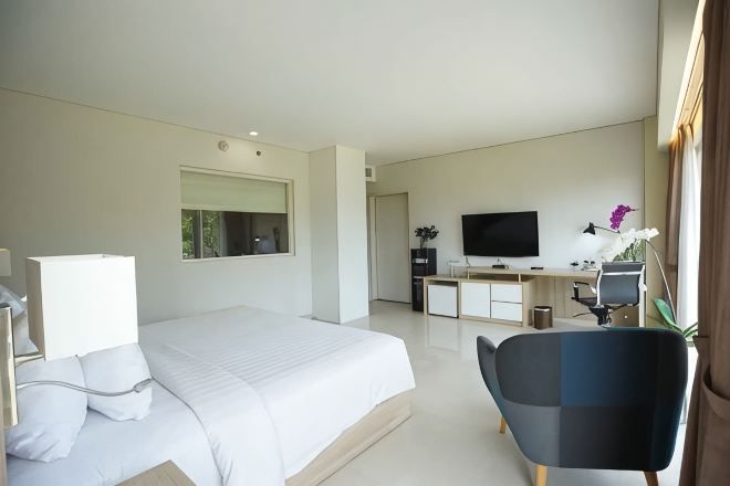 Une chambre d’hôtel moderne avec un grand lit, un bureau équipé d’un ordinateur, une télévision et une chaise.