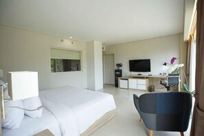 A modern hotel room with a large bed, a desk with a computer, a TV, and a chair. - TreePark Karawang (East Telukjambe)