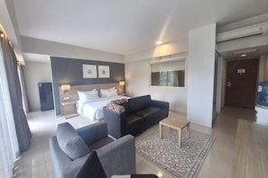 A modern hotel room with a bed, two sofas, a coffee table, and a large window. - TreePark Karawang (East Telukjambe)