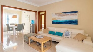 A modern living room with a sofa, a coffee table, and a dining area with chairs and a table.