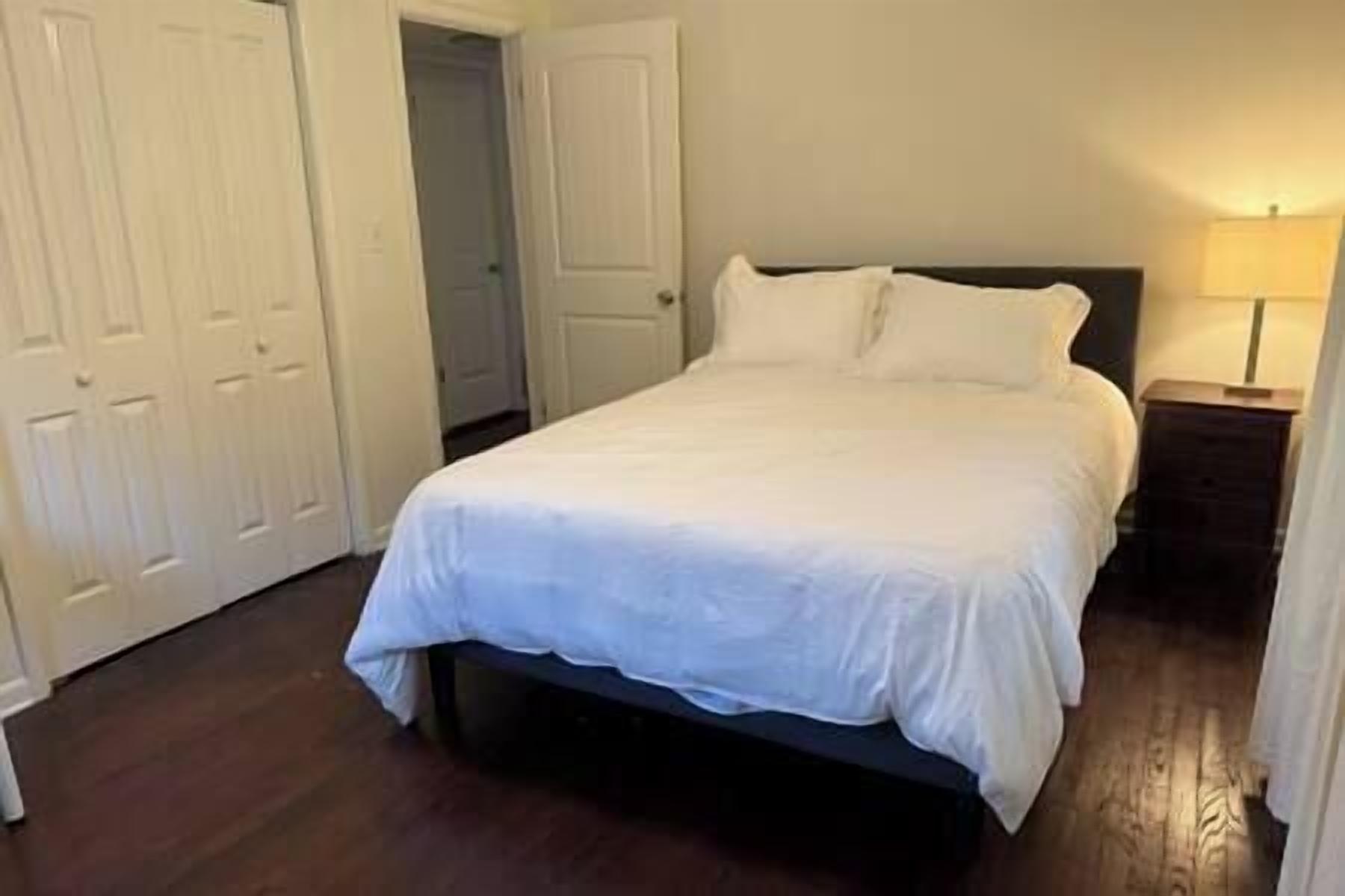 A bedroom with a bed, a nightstand, and a door.