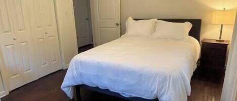 A bedroom with a bed, a nightstand, and a door.