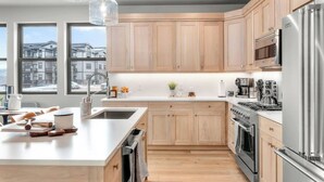 A modern kitchen with wooden cabinets, stainless steel appliances, and a large island with a sink and countertop.