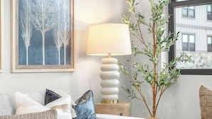 A modern living room with a sofa, a coffee table, a lamp, and a plant.