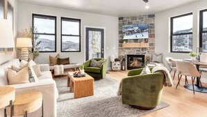 A spacious living room with a fireplace, large windows, and a stone accent wall.
