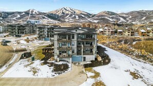 A multi-story residential building with a modern architectural design, surrounded by a snowy landscape and mountains in the background.