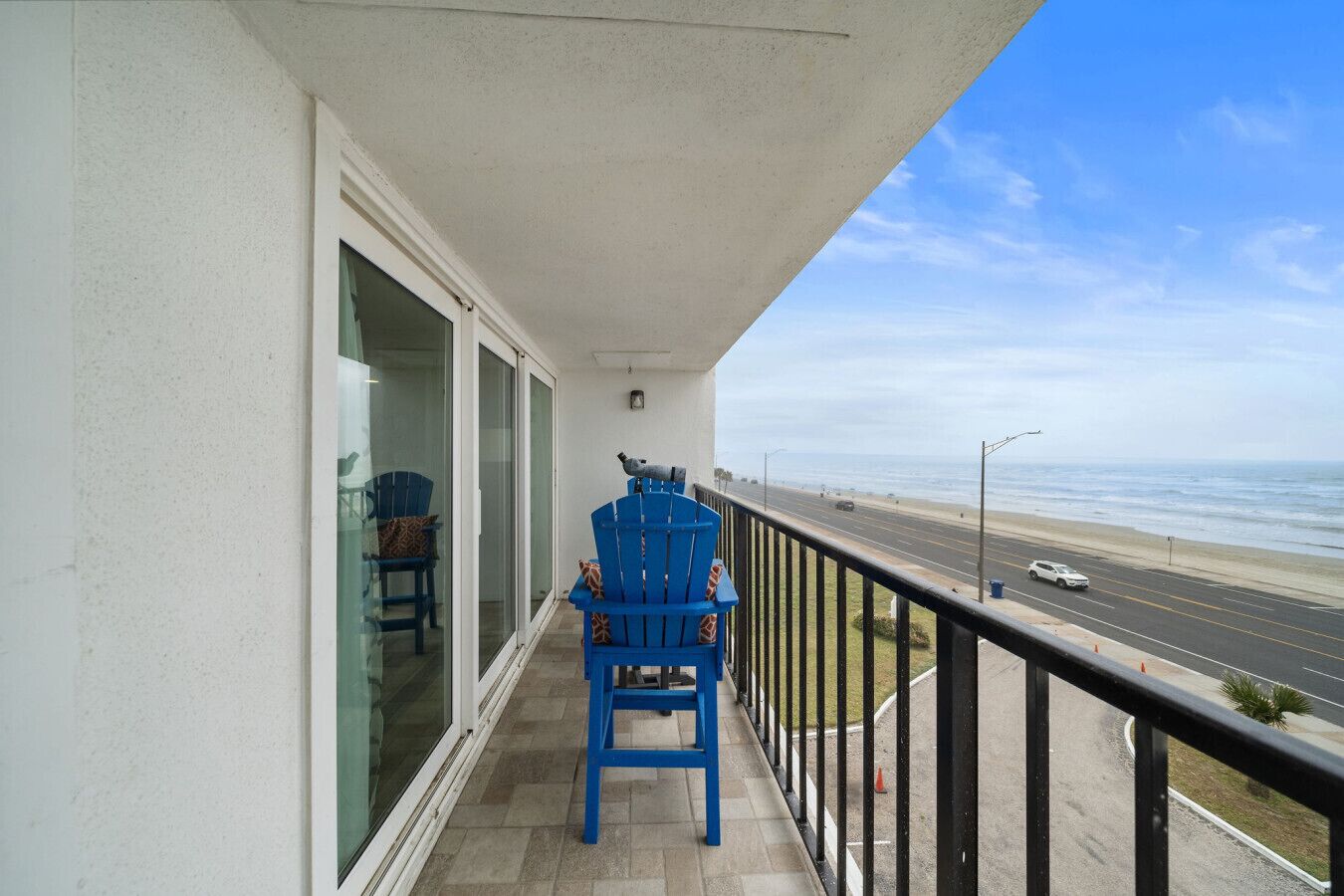 A balcony with a view of the beach and road.