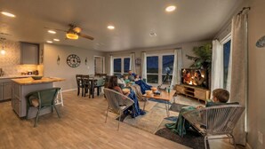 A spacious living area with a kitchen, dining table, and seating for a family. - Charming Beach House Near Water & Fishing (Surfside)