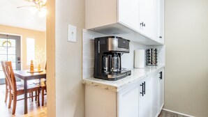 Een keuken met witte kasten, een koffiezetapparaat en een aanrecht.