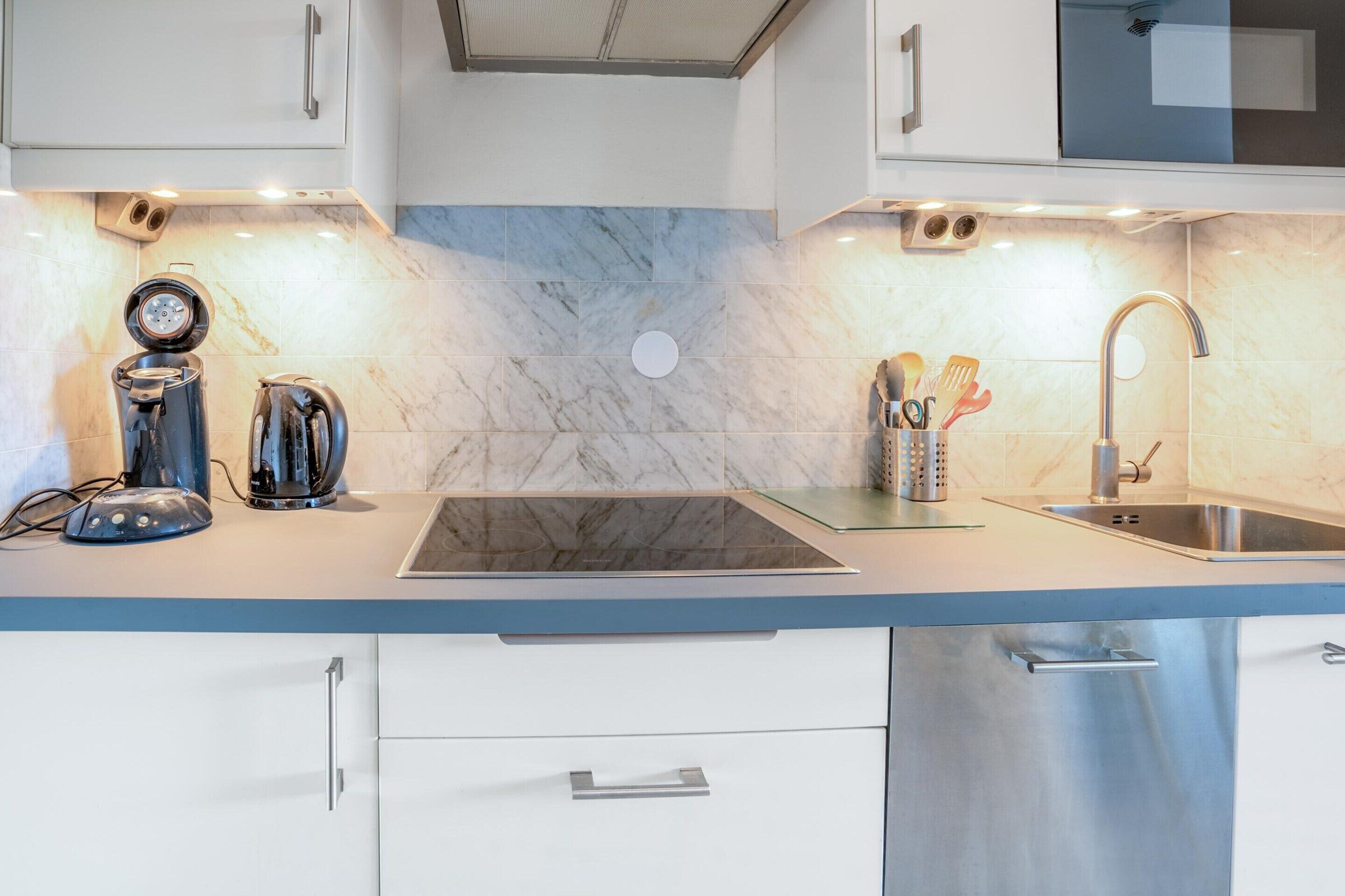 A modern kitchen with a built-in stove, a sink, and a dishwasher.