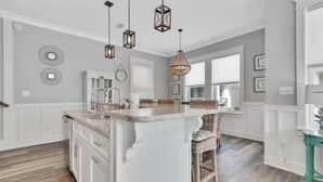 A modern kitchen with a central island, pendant lighting, and a view to the dining area. - 60 seconds to the Beach Harmony Shores Beach, Pool, Lagoon all just steps away (Gulf Shores)