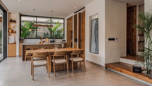 Een moderne keuken met een groot eiland, houten stoelen en uitzicht op groen buiten.