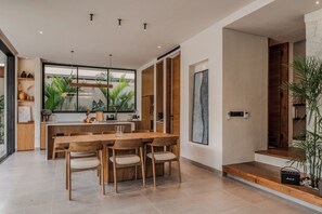 A modern kitchen with a large island, wooden chairs, and a view of greenery outside. - Modern 2 Bed Villa in Bingin, Uluwatu @ Lago Villas (Uluwatu)