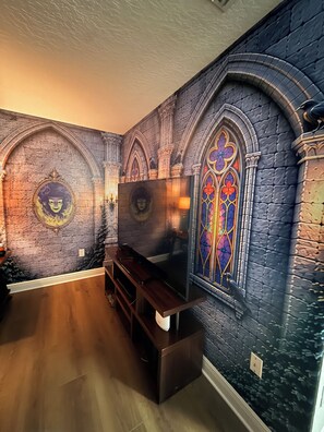 Een kamer met een stenen muur, een houten bank en een flatscreen televisie.