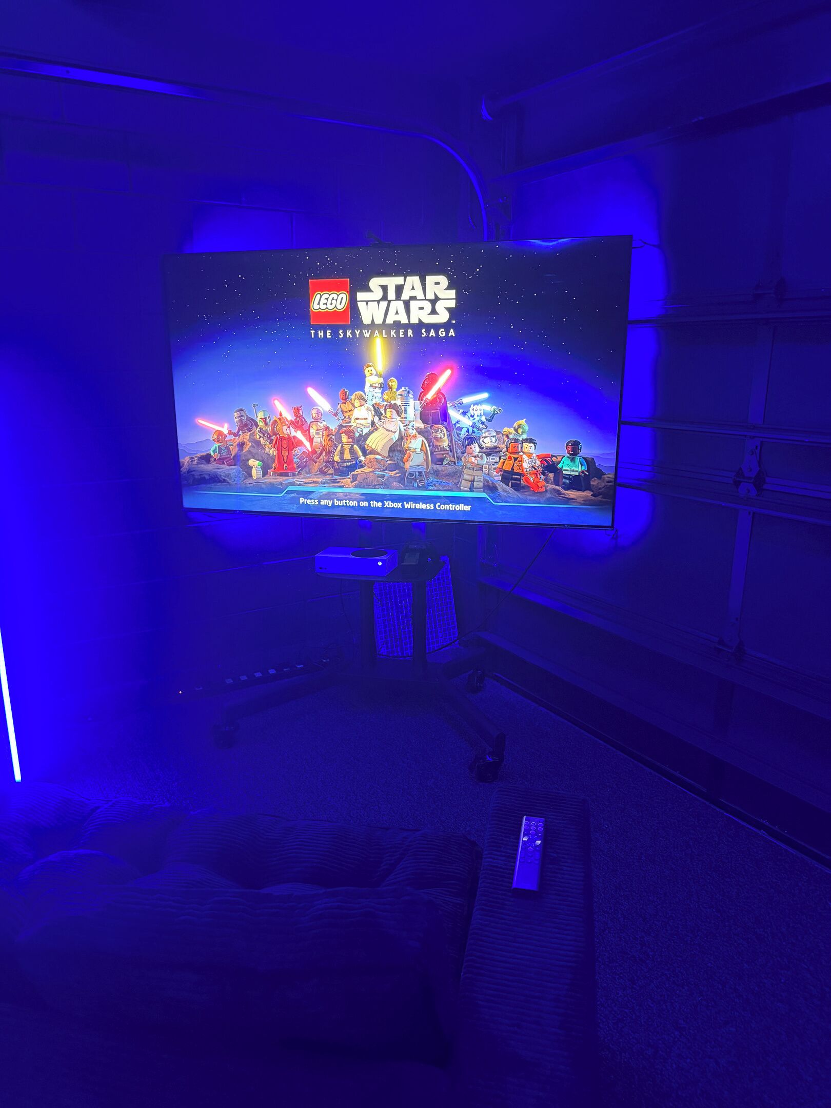 A television displaying a Star Wars LEGO game with a clear instruction to press any button on the Xbox Wireless Controller.