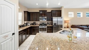 A modern kitchen with dark wood cabinets, stainless steel appliances, and a granite countertop.