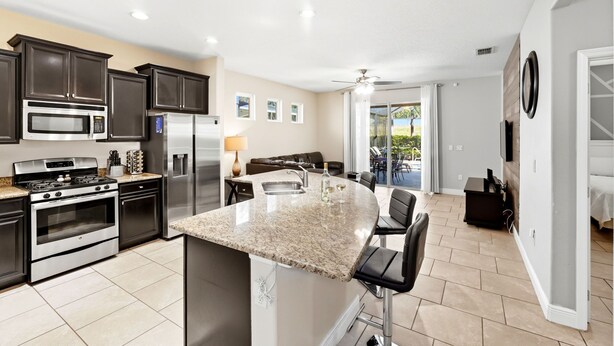 A modern kitchen with granite countertops, stainless steel appliances, and a bar area with bar stools.