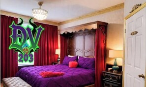 A room with a large bed, red curtains, a chandelier, and a decorative wall.