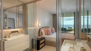 Un dormitorio moderno con una cama grande, una mesita de noche, un lavabo y vistas al mar.