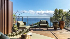 Una terraza con mobiliario exterior, incluyendo un sofá y sillas, y dos macetas grandes.