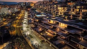 Un complejo hotelero moderno con varios pisos, zonas de estar al aire libre y una calle bien iluminada.
