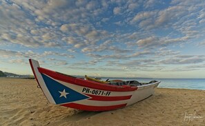 Ein Boot mit einem Stern und der Kennnummer PR-0671-FF an einem sandigen Strand.
