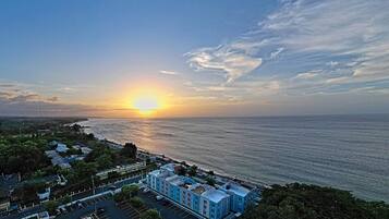 A coastal hotel with a view of the sunset over the ocean.