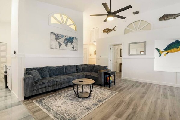 A modern living room with a sectional sofa, a round coffee table, and a ceiling fan.