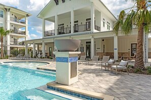 A pool area with lounge chairs and a large building with balconies.