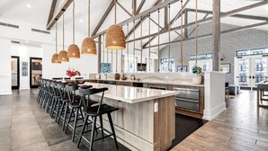 Une cuisine moderne dotée d’un îlot central, de tabourets de bar, de luminaires suspendus et offrant une vue sur la ville grâce à de grandes fenêtres.